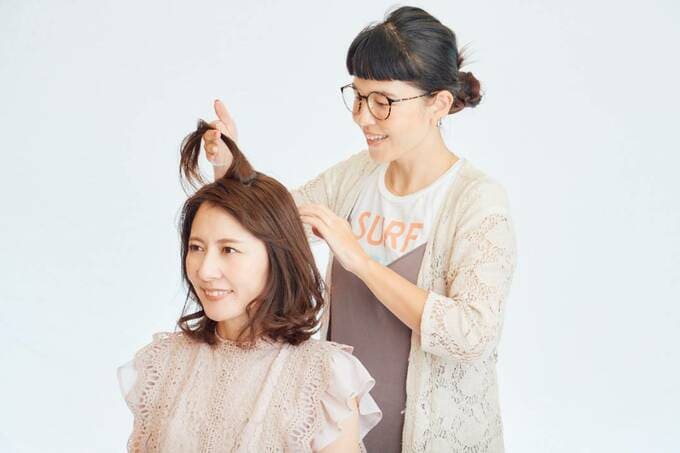 客の髪をチェックする美容師