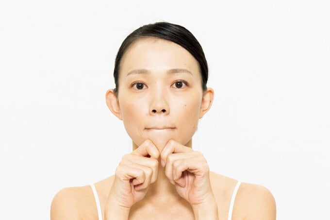 曲げた人さし指をあごに当て、口を閉じた女性