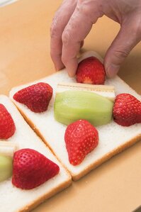 （2）　食パンの中央にキーウィとバナナを斜めに並べ、四つ角にそれぞれイチゴの先端部分を合わせて置く