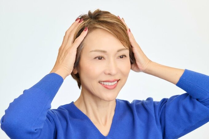 髪の表面をなでる女性