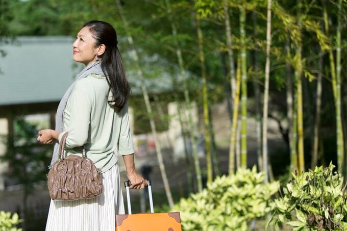 温泉地でスーツケースをひく女性