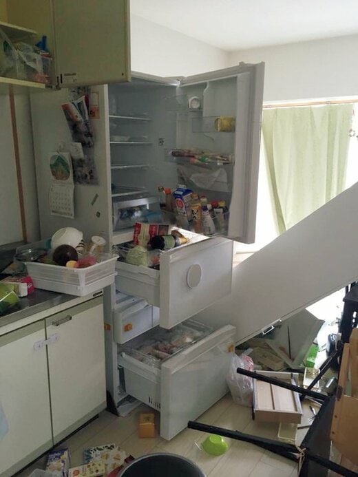地震により庫内のものが飛び出た冷蔵庫と散らかったキッチン