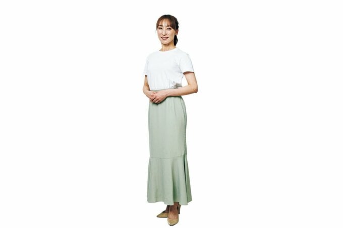 白のトップス・ライトグリーンのロング丈スカートをはいた女性