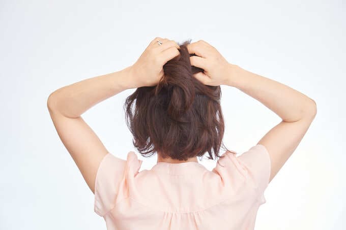 耳上の髪にワックスやバームをなじませ、手ぐしで髪をまとめる