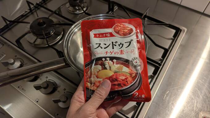 キッチンコンロの上でスンドゥブチゲの素を持っている