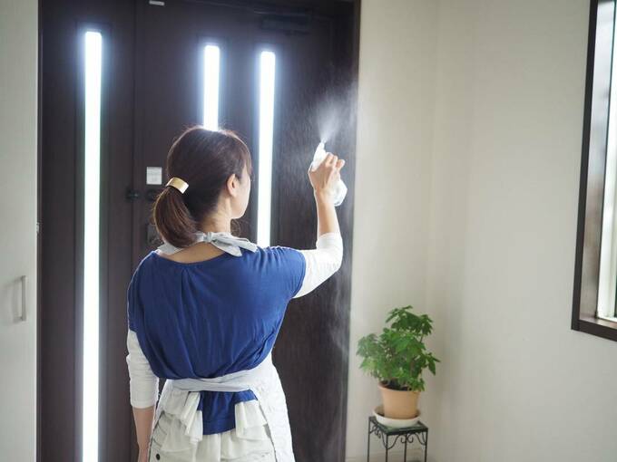玄関を消毒する女性