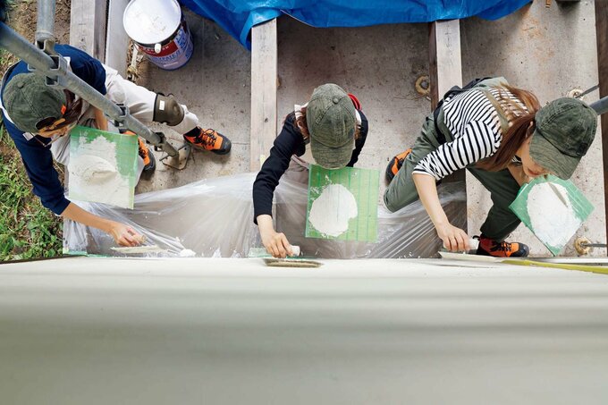 外壁を仕上げていく3人