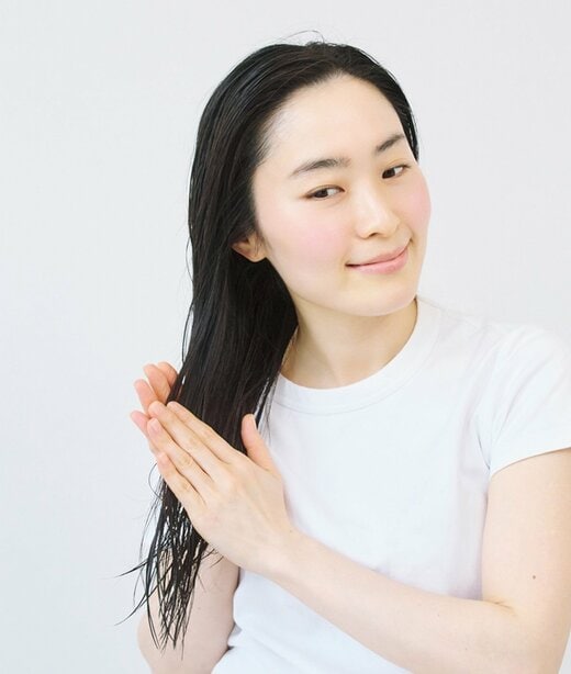 両手のひらで髪をはさむ女性