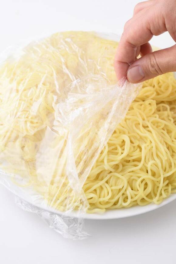 チンした麺のラップをはずす様子