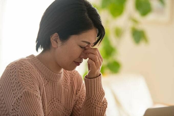 目頭をおさえる女性