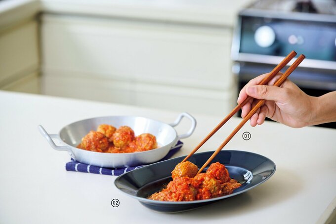 皿に盛り付けられたミートボールを菜箸でつかんでいる様子