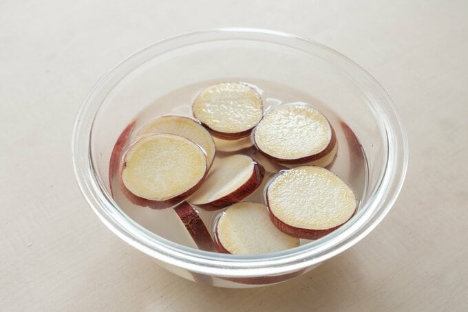 さつまいもをボールの中で水にさらしている