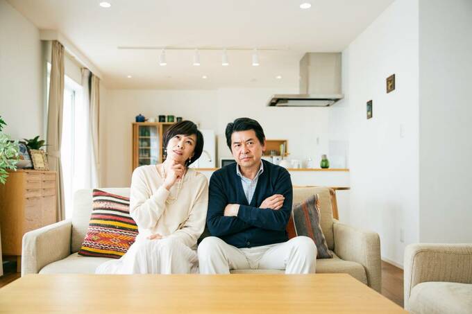 ソファーに座って考え事をする夫婦