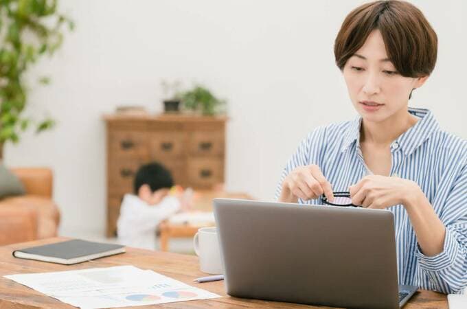 パソコンの前にメガネを持つ女性