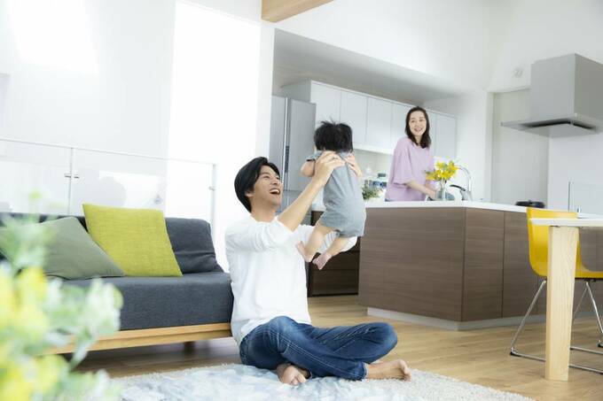 子どもを抱っこする男性とキッチンに女性