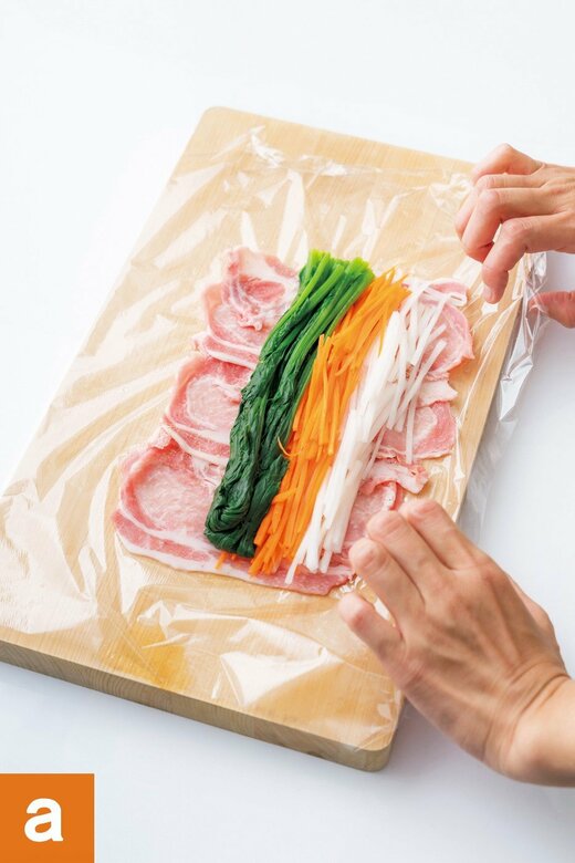 ラップに豚肉を並べて野菜をのせた状態