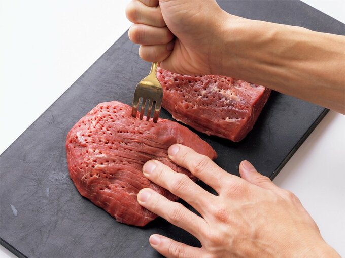 牛モモかたまり肉にフォークで穴をあけているところ