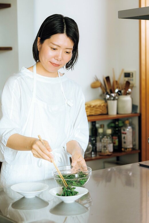 ボウルから皿へ料理を盛りつける女性