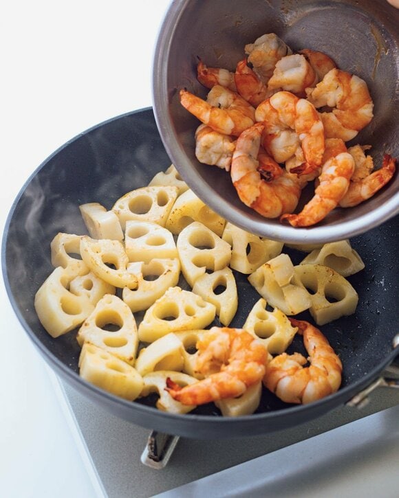 レンコンが入ったフライパンにエビを入れる様子