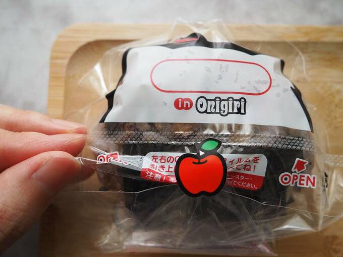 フィルムに包まれたおにぎりのフィルムをつかむ様子