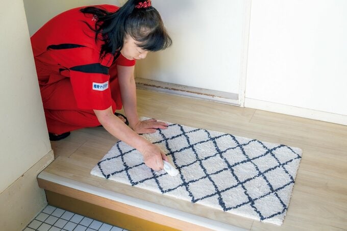 玄関マット掃除をする新津さん