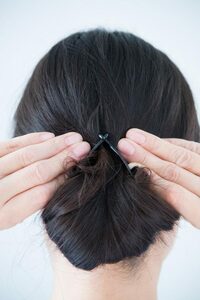 手に持った両端のフックをまとめた髪の上で引っかけて留める