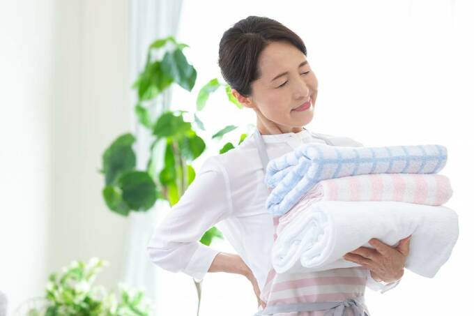 タオルを持って腰をおさえる女性