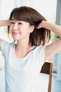 女性両手で髪をかきあげる