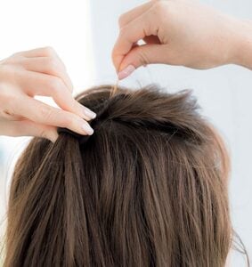 右手で髪をつまみ上げる