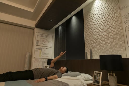 ベッドに寝て指差す男性