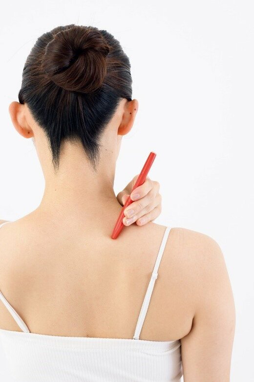 ペンを使ってツボ押しをする女性