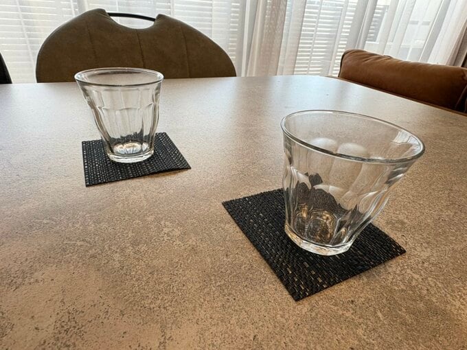 黒いコースターの上にガラスのコップが置かれているダイニングテーブル