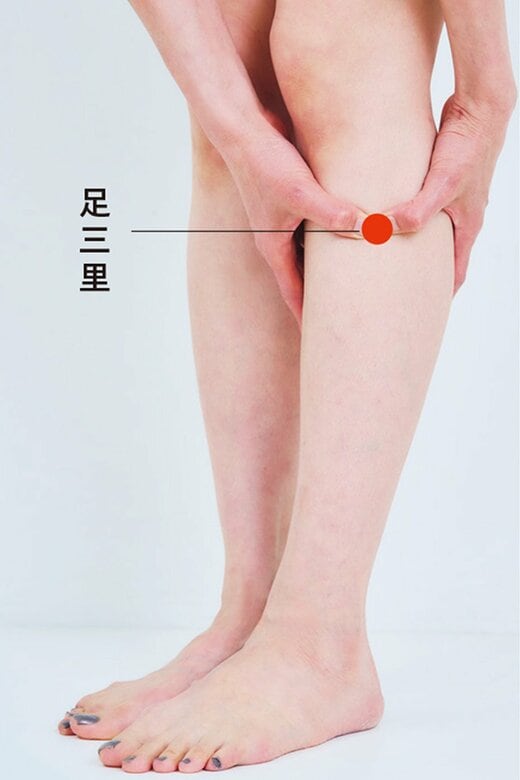 ひざの外側お皿の下から指4本分下がったとろにあるツボを両手で押す様子