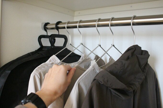 ハンガーにかかった服を取ろうとしている手