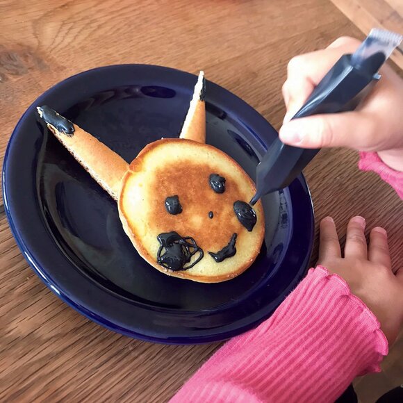 ホットケーキにチョコレートで顔を描く様子