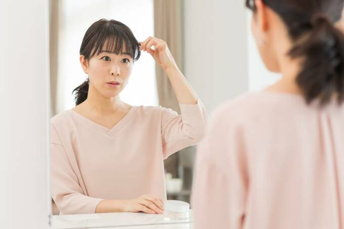 鏡の前で髪を触る女性