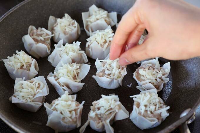 フライパンの上のシューマイにチーズをのせる