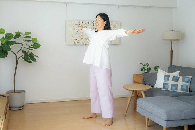 リビングで両手を横に広げる女性