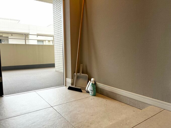 玄関と、玄関の隅に置かれたほうきとちりとり