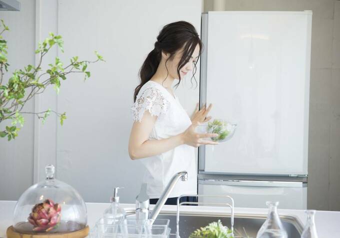 冷蔵庫の前で野菜を持つ女性