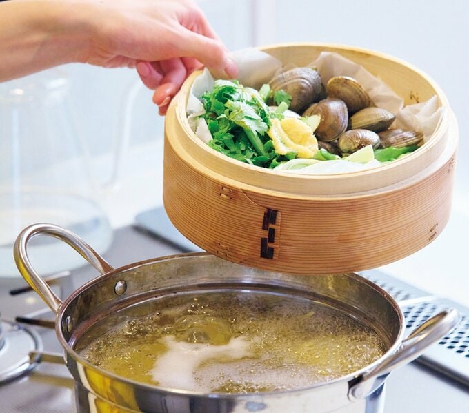 パスタをゆでている鍋の上に、アサリと香味野菜が入ったせいろをのせるところ