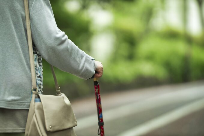 杖をついて歩く女性